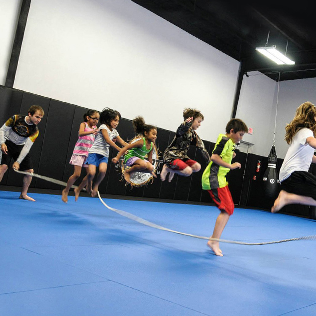 Kids of various ethnicity and ages jumping rope in a martial arts and fitness gym
