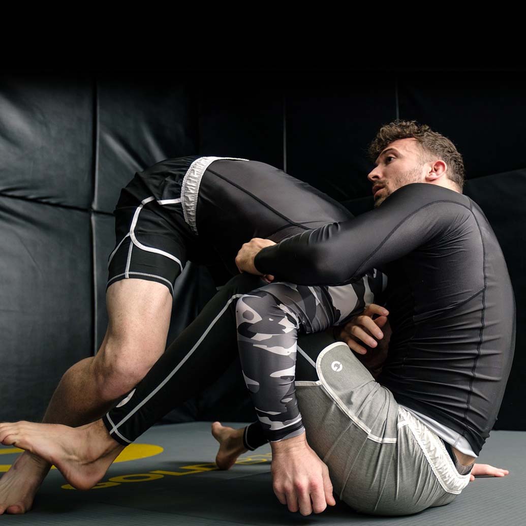 2 grown men practicing jiu-jitsu in a martial arts facility