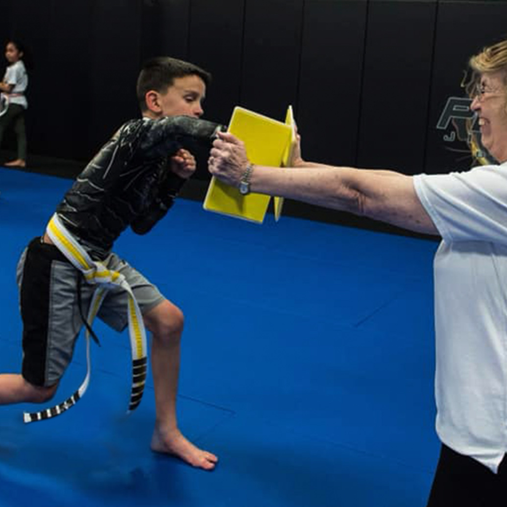a young boy at the kids age and skill level breaking a yellow board in martial arts class
